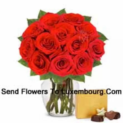 11 Trandafiri roșii cu câteva ferigi într-un vas de sticlă însoțiți de o cutie de ciocolată importată