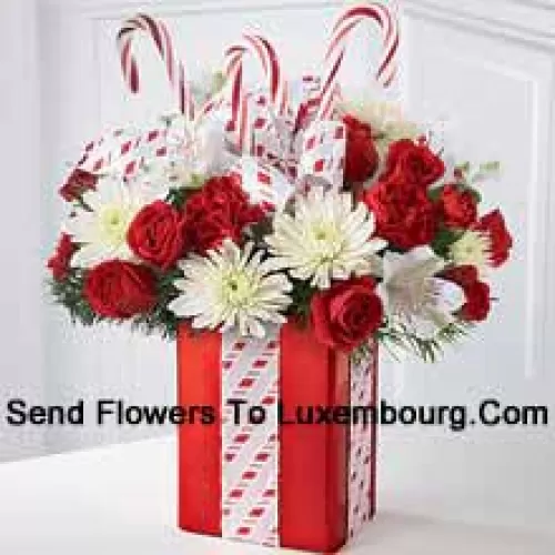 この花束は、その気まぐれな喜びと元気な美しさで彼らを魅了するでしょう！白いマム、赤いカーネーション、スプレーバラの美しいアレンジメントが、キャンディケインで飾られた輝く赤い花瓶の中にホリデーグリーンと共に座っており、美しいリボンで完璧に包装されている姿は、まるで最高のホリデーギフトのように見えます。（特定の商品が入手できない場合は、同等価値の適切な商品に交換する権利を留保します）